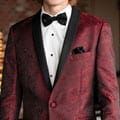 A young man in a burgundy suit rental.