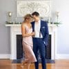 A bride and groom, dressed in their Michael Kors Blue Performance wedding attire, standing in front of a fireplace.