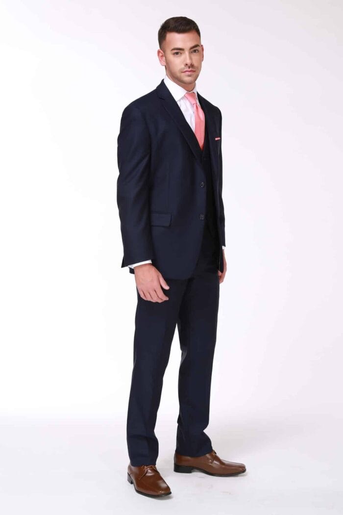 A man is posing for a photo in an After Six Navy Rivera suit rental.
