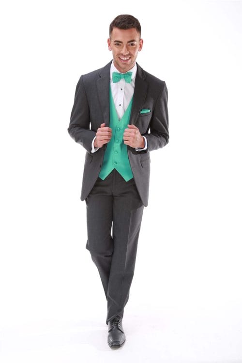 A man in an Allure Charcoal tuxedo, available for suit or tuxedo rental, with a green bow tie.
