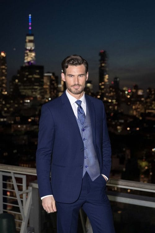 A man in an Allure Charcoal suit rental standing on a rooftop at night.