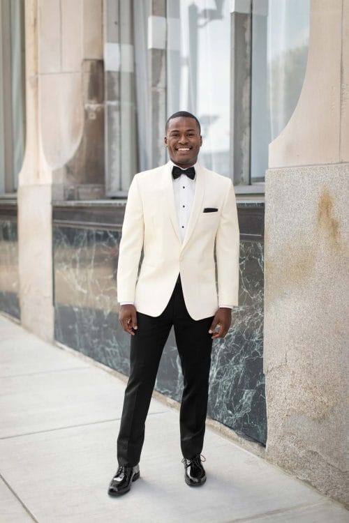 A man in an Allure Charcoal tuxedo poses for a photo.