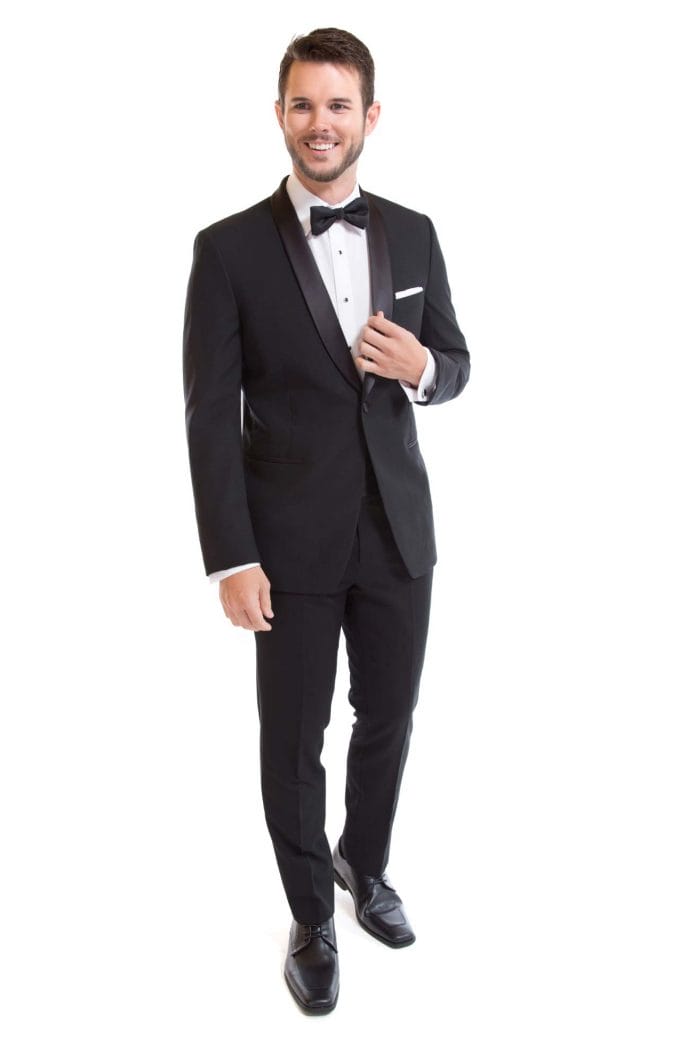 A man in an Allure Charcoal tuxedo posing for a photo during a suit rental event.