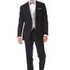 A man in an Allure Charcoal tuxedo is standing in front of a white background, showcasing the elegance of suit rental.
