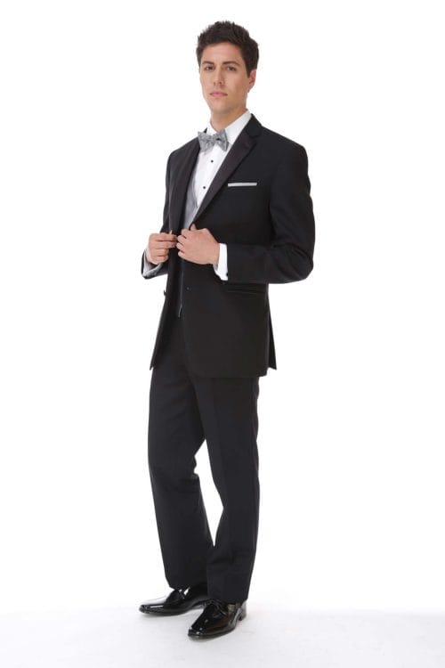 A man in a black tuxedo posing for a photo, showcasing the Allure Charcoal suit available for tuxedo rental.
