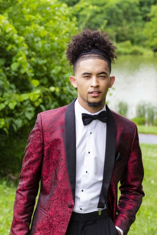 A young man in an Allure Charcoal tuxedo posing for a photo during a tuxedo rental.