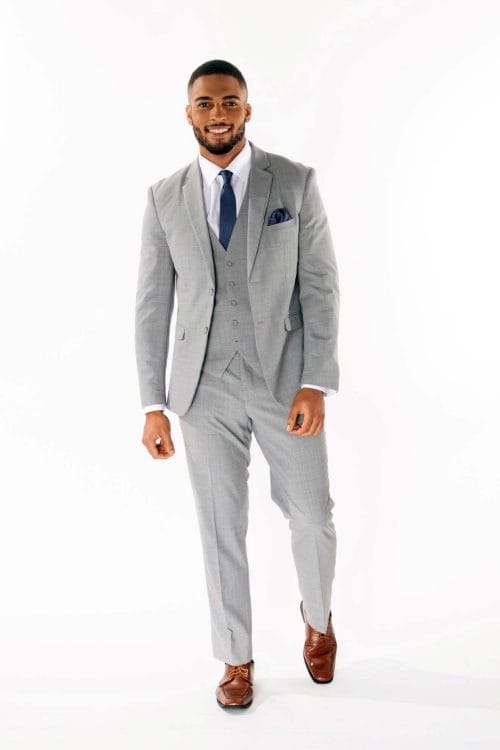A man in an Allure Charcoal suit poses for a photo at a suit rental.