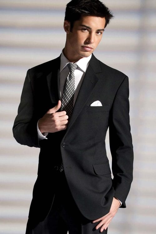 A man is posing in an Allure Charcoal suit.
