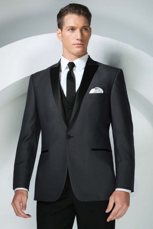 A man in an Allure Charcoal tuxedo rental is posing for a photo.