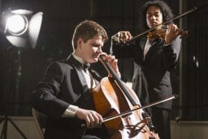 Two young men in tuxedo playing cello.
