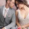 The bride and groom, dressed in their elegant Allure Heather Grey suits from a tuxedo rental service, sit lovingly together on a couch.