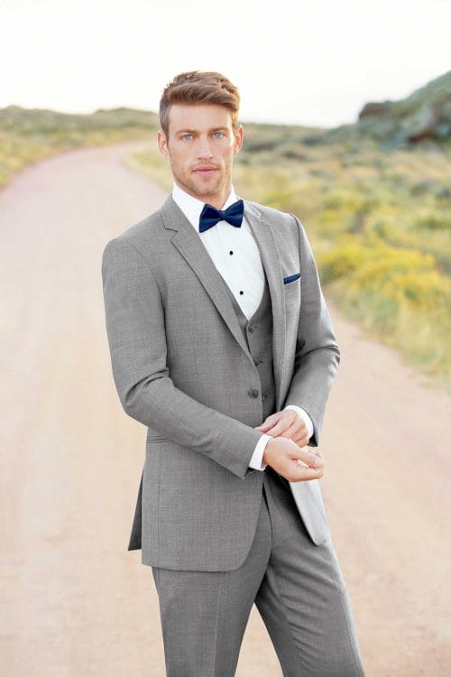 A man in an Allure Heather Grey rental standing on a dirt road.