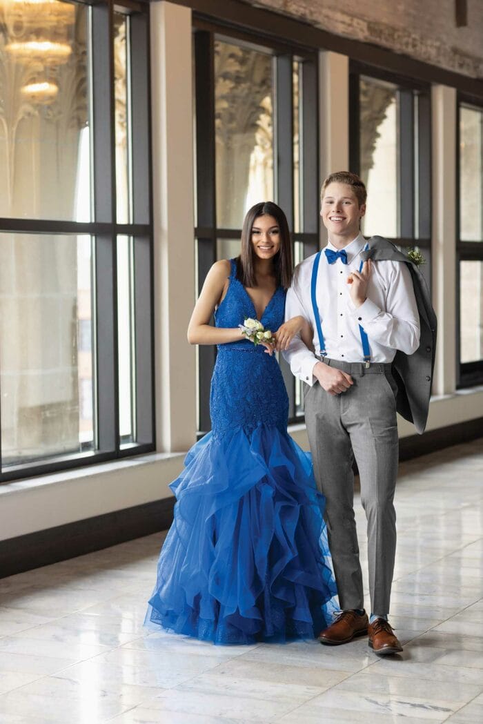 A man in a tuxedo and a woman in a blue dress pose for a photo.