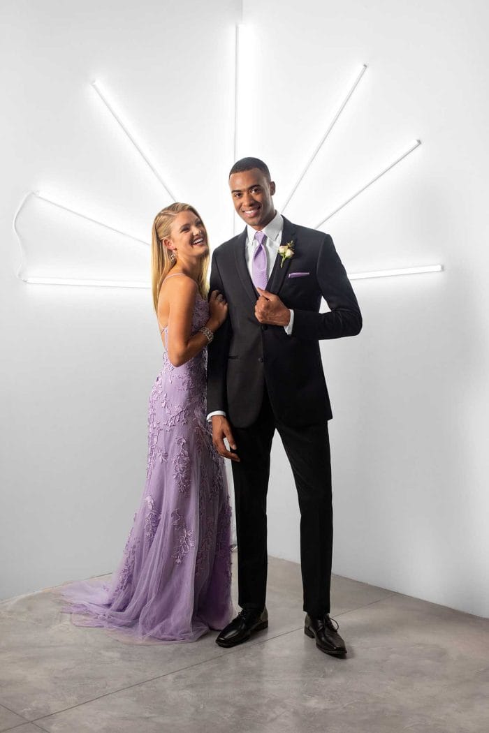 A man and woman, dressed in elegant attire from Michael Kors Berkeley, posing in front of a neon light.