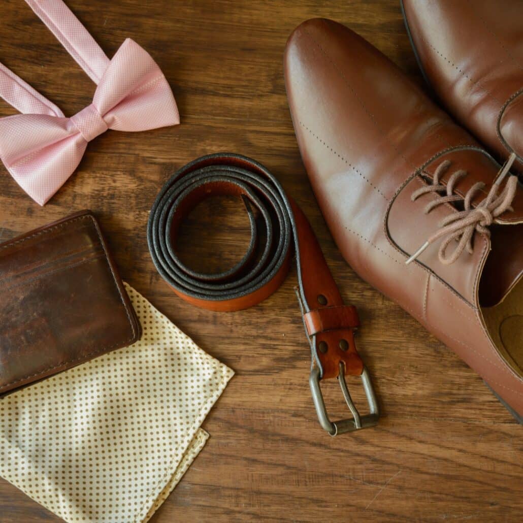 A pair of brown shoes and a bow tie on a wooden table.