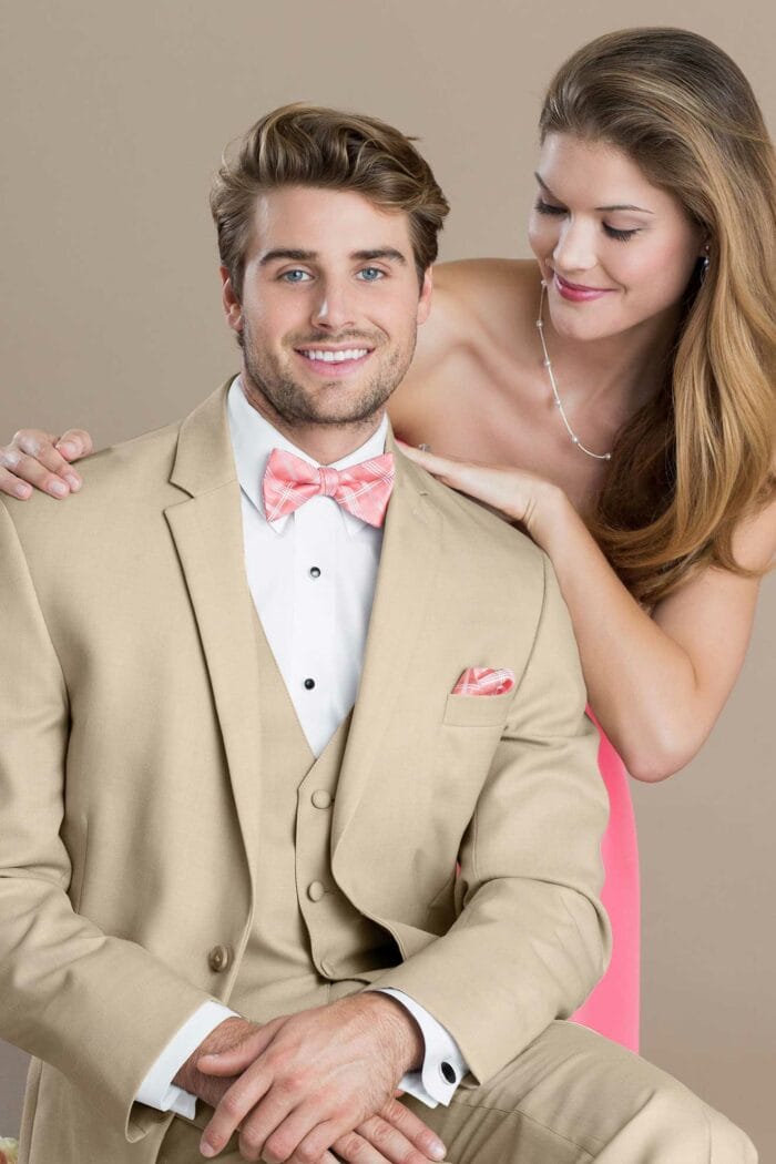 A man in a Lord West Tan Havana tuxedo and a woman in a pink dress at a suit rental shop.