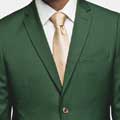 A man in a green suit is posing for a photo after his tuxedo rental.