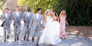 A group of bridesmaids and groomsmen in tuxedo rentals walking down a road.